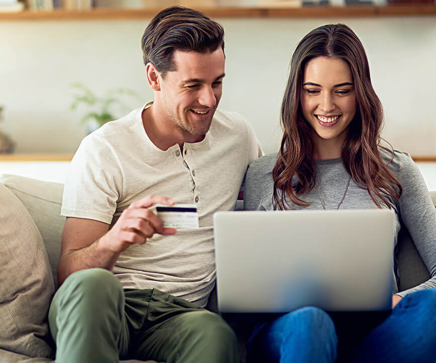 young couple sitting on the couch, paying a bill online together