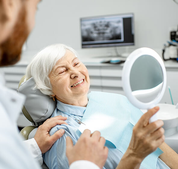 senior woman examining her smile in a mirror