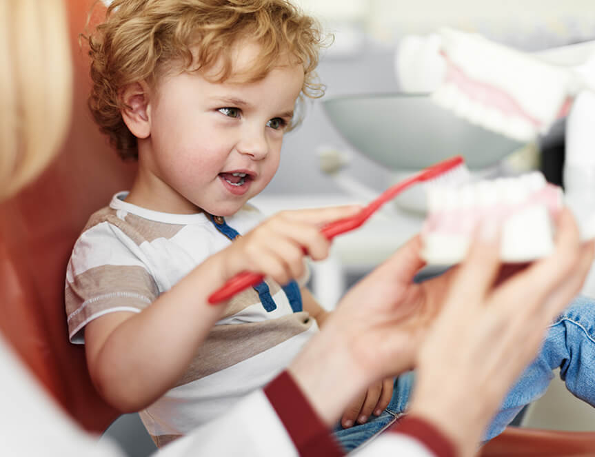 young boy learning how to brush his teeth