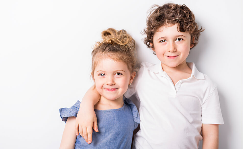 brother standing next to his sister with his arm around her