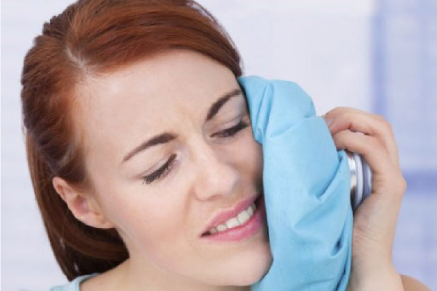 woman holds an icepack to her face after wisdom teeth removal