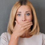 woman covers her mouth to hide receding gums