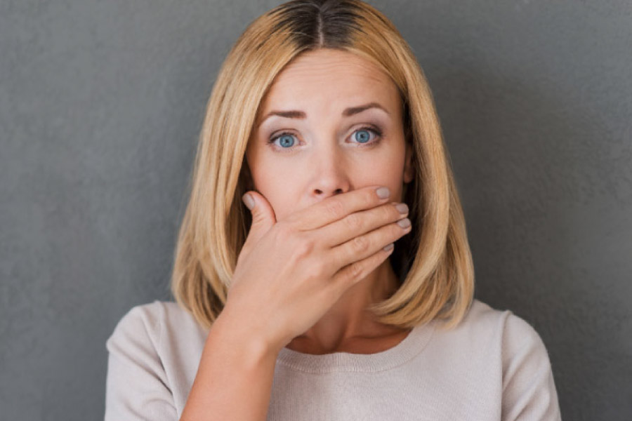 woman covers her mouth to hide receding gums