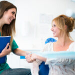 female dental employee greets a young woman to put her at ease.