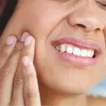 woman holds her jaw in pain with a root canal infection