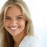 young blond woman smiles showing off her teeth whitening results.
