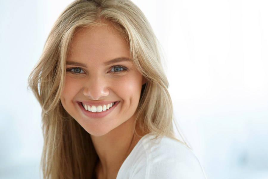 young blond woman smiles showing off her teeth whitening results.