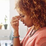 woman holds the bridge of her nose with a sinus issue caused by wisdom teeth