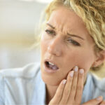woman holds her jaw in pain from tooth sensitivity